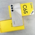 A sleek smartphone placed on a vibrant yellow box against a gray background, showcasing modern technology.